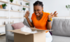 Emotionen beim Online-Handel: Eine Frau freut sich beim Aufmachen eines Pakets
